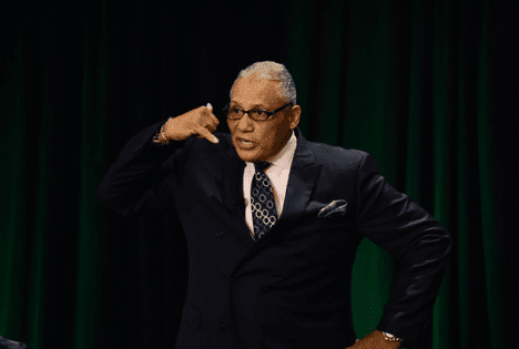 A man in a suit and tie holding his hand up to his ear.