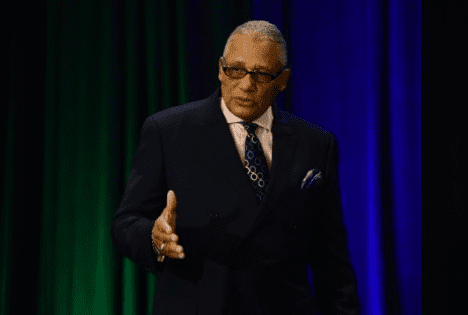 A man in a suit and tie talking on stage.